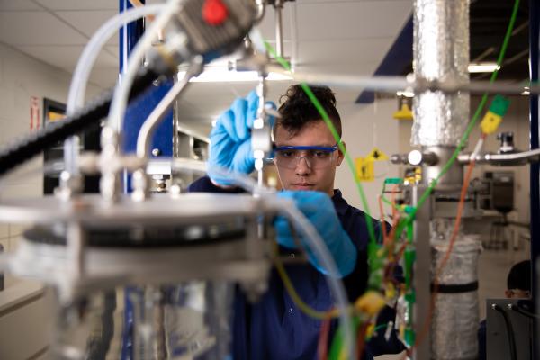 Student focusing on an experiment, taken through a web of wires and metal plates.