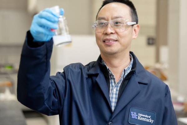 Photo of Jian Shi holding glass container in a lab