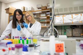 Researchers in a lab with colorful lab equipment surrounding them.