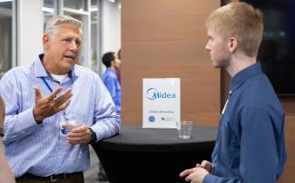 A potential employer from Midea talking to a student at a career connections event.