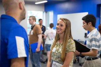 Student talking to a recruiter at a with other students milling around in the backgroud.