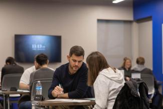 An alumni helping a student with school work.