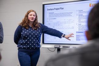 Student in front of a TV giving a presentation.