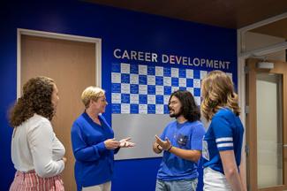 Staff member talking to 3 students in front of a sign that says "Career Development."