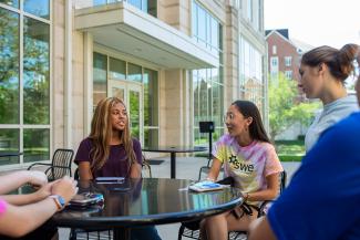 Students sitting outside at a table talking.