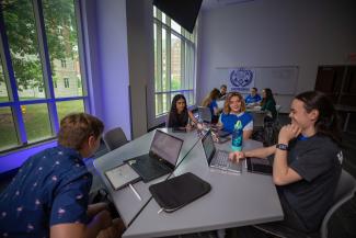 Students around a table studying in a dorm classroom