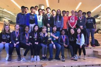 Students on "The Steps" in the Gatton student center, holding a trophy and wearing medals.