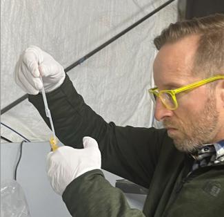 Researcher James Keck pipettes wastewater into a PCR tube for analysis.