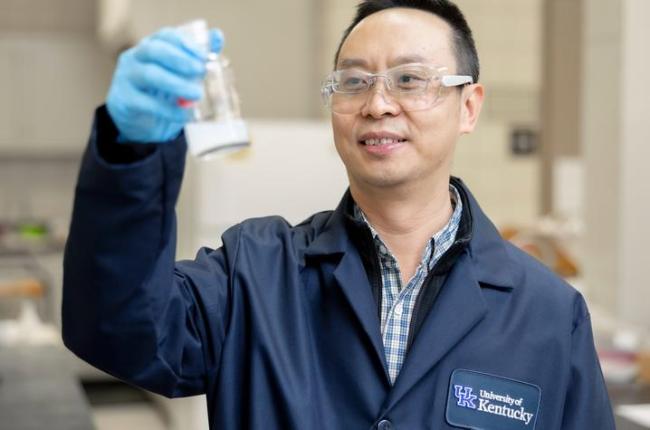 Photo of Jian Shi holding glass container in a lab