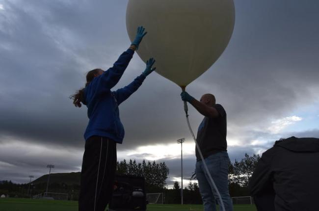 Two people holding a balloon.