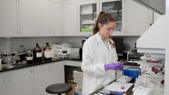 Student Isabella Ritz wearing a white coat and working in a lab.