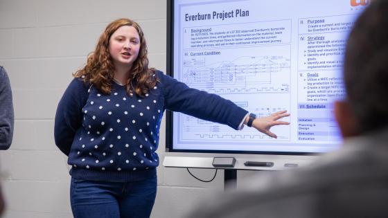 Student in front of a TV giving a presentation.