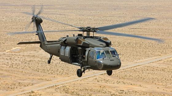 Black hawk military helicopter flying over a desert landscape.