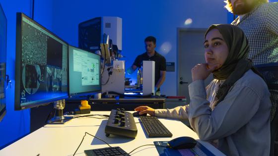 Student researchers looking at computer screen with technology it the background.