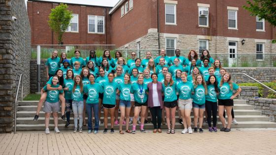 Group of WiE Camp students standing on steps, wearing matching t-shirts.