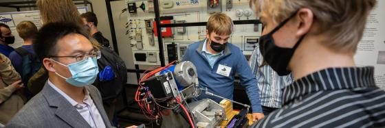 A professor talking to a student (both wearing COVID masks) about the senior design project.
