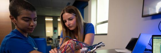 Two women working on a bionic arm.