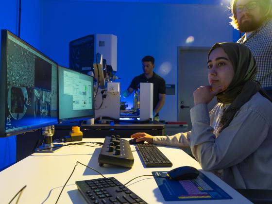 Student researchers looking at computer screen with technology it the background.