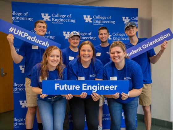 Student standing in front of step and repeat with welcome signs